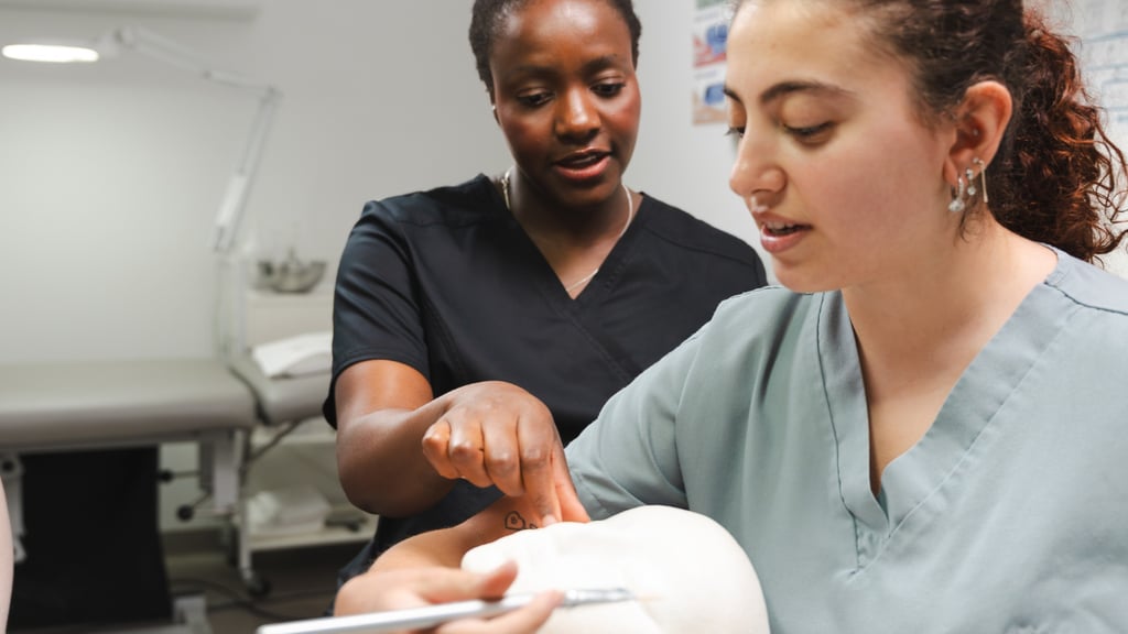 A clinician instructing and supervising a student whilst they practise a brush on facial treatment